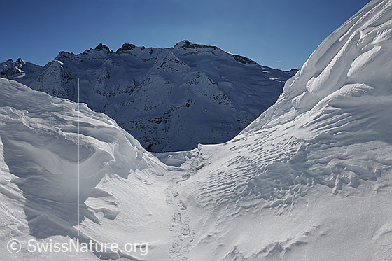 Foto: Blick aus einer mächtigen Wächte in die schattigen Nordflanken der Schinhörner.
