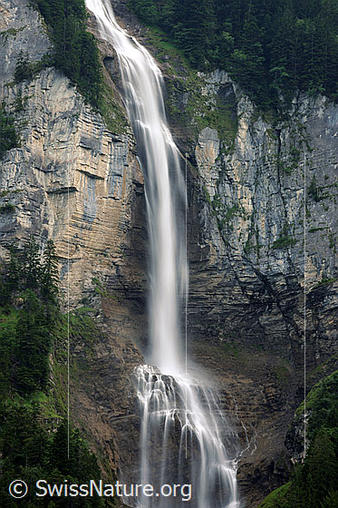 Foto: Ein Wasserfall stürzt über eine hohe Felswand und trifft auf einen Felsvorsprung (Langzeitaufnahme).