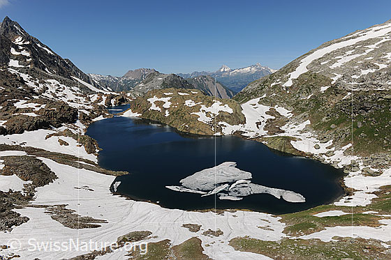 Foto: Berglandschaft und dunkelblaue Seen (Geisspfadsee und Züesee) mit Eisschollen. Die Bergseen sind noch von Schneefeldern umgeben.