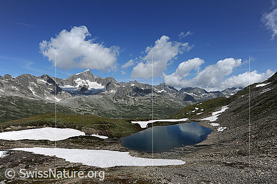 Foto: Galenstock und Schwärziseeli. Blauer Bergsee in Berglandschaft mit Schneefeldern und Quellwolken über den Berggipfeln.