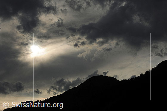 Foto: Gewitterstimmung mit dunklen Wolken über der Kontur einer Berglandschaft.
