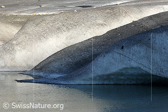Foto: Ende der Gletscherzunge des Rhonegletschers in Gletschersee mündend. Auf das Gletschereis fällt Licht und Schatten.
