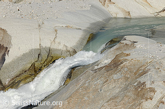 Foto: Quelle der Rhone. Hier noch als schmaler, schäumender Gletscherbach beim Ausfluss aus dem Gletschersee. Das Wasser fliesst über geschliffene Felsen (Gletscherschliff, Aaregranit).