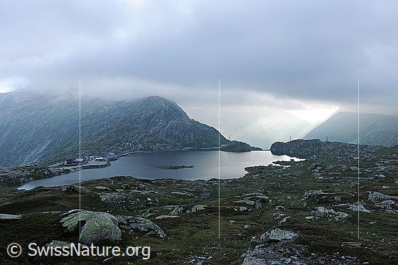 Foto: Stimmung über dem Grimselpass. Licht dringt durch die Wolkendecke über dem Alpenpass mit Bergsee (Totesee).