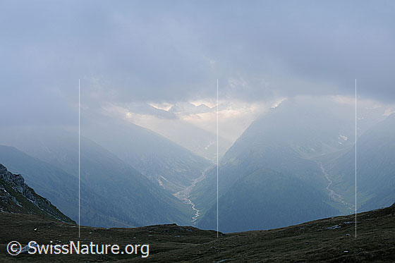 Foto: Geretal und Gonerli mit schwachem Lichtschein, welcher in die Bergtäler fällt. Darüber liegt eine Wolkendecke.