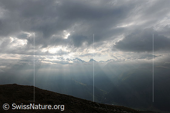 Foto: Lichtstimmung und Wolken. Lichtstrahlen brechen durch die Wolkendecke über der Berglandschaft.
