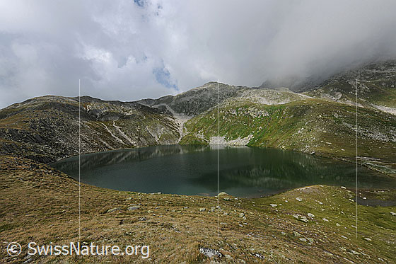 Foto: Rundsee, Obergoms. Starke Quellbewölkung liegt über der Berglandschaft, welche sich im Bergsee spiegelt.