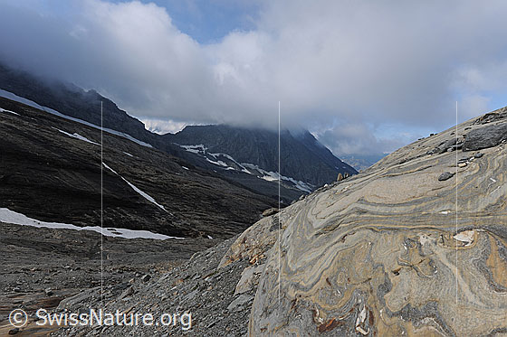 Foto: Gletscherschliff auf marmoriertem Fels. Die Oberfläche, des vom Chaltwassergletscher abgeschliffenen Felsens weist interessante Formen und Muster in unterschiedlicher Farbe auf. Steine, die der Gletscher mitgeführt hat, sind auf dem glatten Fels liegen geblieben. Über dem urtümlichen Gletschervorfeld befindet sich ein tief hängendes Wolkenfeld.