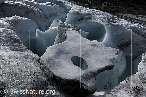 Foto: Eisskulptur aus Gletschereis über einem Eiskanal auf dem Chaltwassergletscher. Durch das Loch im Eis ist das Schmelzwasser des Gletscherbachs zu sehen. Supraglazialer Schmelzwasserkanal.