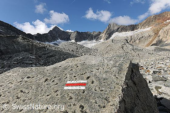 Foto: Markierung Bergweg an Felsblock am Gletscherrand des Gruebengletschers. Im Hintergrund sind Gross Diamantstock und Hiendertelltihorn zu sehen.