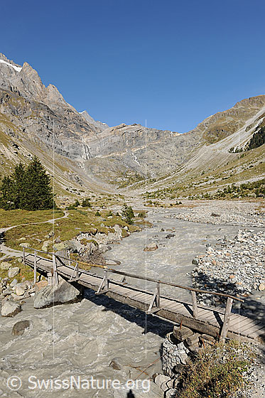 Foto: Brücke über die Kander. Der Wandweg führt dem Fluss entlang in die Berglandschaft im hinteren Teil des Gasteretals. Der Holzsteg über die Kander wurde durch eine Hängebrücke ersetzt. Im Gasteretal hat die junge Kander noch weitgehend freie Hand.