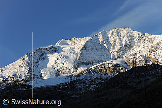 Foto: Verschneite Les Diablons und Diablonsgletscher mit Licht und Schatten. Am blauen Himmel sind Schleierwolken zu sehen.