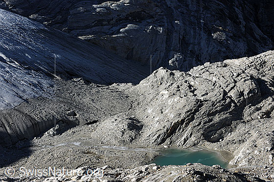 Foto: Gletscherzunge Brunegggletscher und Gletschersee. Die Gletscherlandschaft liegt im Licht und Schatten. Im Wasser sind Eisreste zu sehen.