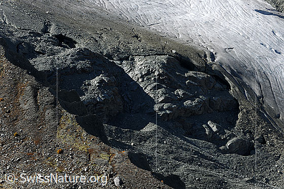 Foto: Randbereich Turtmanngletscher mit Felsen und Hohlräumen unter dem Gletschereis. Im Vordergrund ist ein Teil der Seitenmoräne sichtbar.