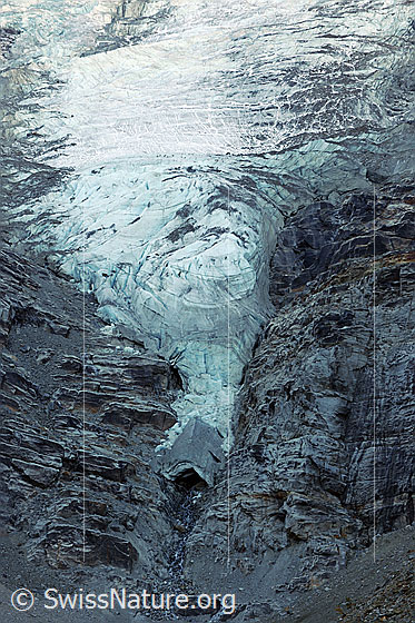 Foto: Zunge des Riedgletschers und Gletschertor. Die Gletscherzunge endet in einem steilen Felsabschnitt. Das Gletschereis am schmalen Zungenende ist eingebrochen.