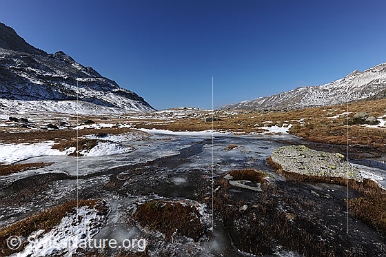 Foto: Eisschicht über Wasserlauf in der Weite einer herbstlichen Hochebene.