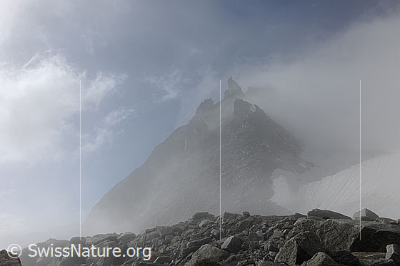Foto: Geheimnisvolle Wolkenstimmung am Gerenpass. Durch den Nebelschleier ist der Poncione di Cassina Baggio erkennbar. Im Vordergrund ist ein Wall aus Geröll und Felsblöcken zu sehen.