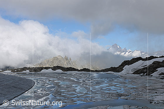 Foto: Mit Eisschollen bedeckter Gletschersee und rund geformter Gletscherrand. Über der Berglandschaft mit Finsteraarhorn und Agassizhorn reissen die Wolken stimmungsvoll auf. Die Eisreste der schmelzenden Eisdecke bilden ein Muster auf der Wasserfläche.