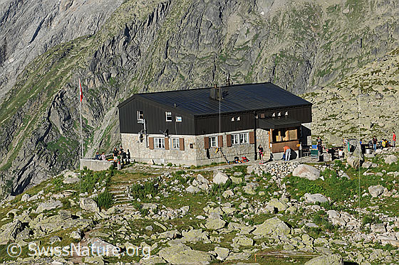 Foto: Bergseehütte des SAC. Rund um die Hütte haben sich einige Wanderer eingefunden.