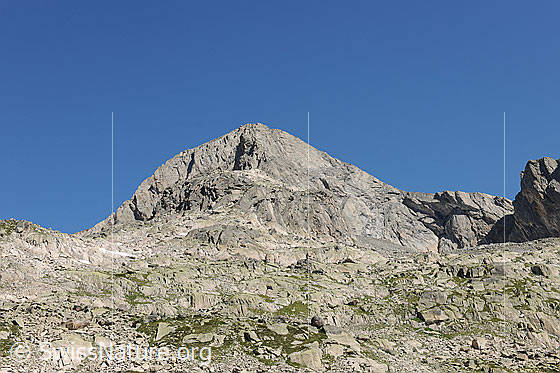 Foto: Schijenstock umgeben von Blockgelände und blauem Himmel. Die Felswände aus Granit gehören zum Klettergebiet um die Bergseehütte.