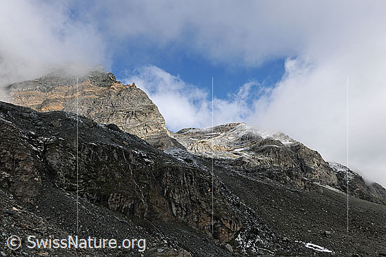 Foto: Wolkenstimmung am Schwarzberg mit Licht und Schatten. In den Felsenwänden sind Felsformationen und bräunliche Felsbänder erkennbar.