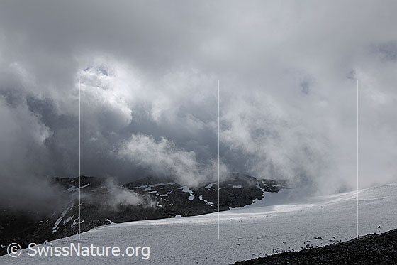 Foto: Dramatische Wolkenstimmung über dem Gletscher. Aufreissende Wolken über dem Schwarzberggletscher lassen etwas Licht auf die noch im Schatten liegende  Gletscherlandschaft scheinen.