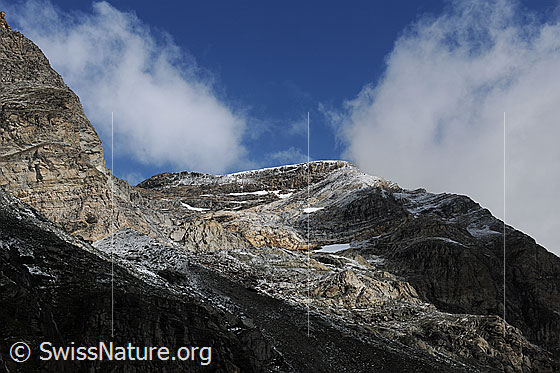 Foto: Stimmung am Schwarzberg. Wolkenstimmung in den Felsen des Schwarzberg mit Licht und Schatten. In den Felsenwänden sind Felsformationen und bräunliche Felsbänder erkennbar.