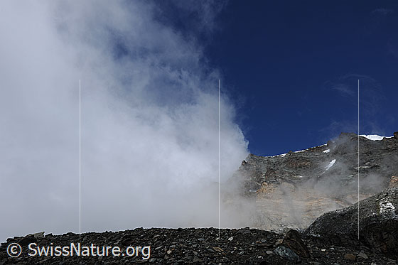 Foto: Wolkenstimmung über der Moräne des Schwarzberggletschers. An den Felswänden und Graten von Strahlhorn und Fluchthorn ziehen Wolkenfetzen vorüber.