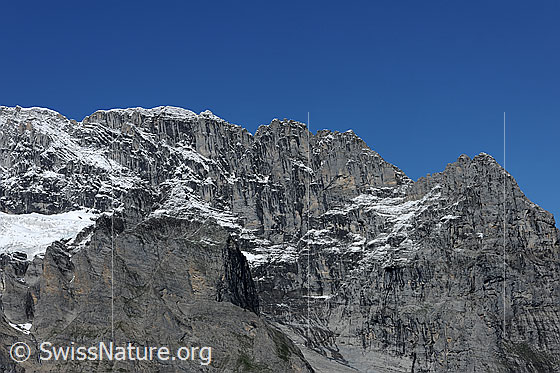 Foto: Hörnli am Eiger. 
Felsgrat mit den Hörnli und Blick in die steil abfallenden Felswände. Auf den Felsstufen liegt etwas Neuschnee.