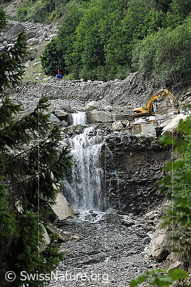 Foto: Murgang Spreitgraben (Spreitlauigraben, Grimselpass) . Unter den Geröllmassen befindet sich eine Galerie der Grimselpassstrasse. Mit einem Bagger werden die beschädigten Bauten freigelegt.