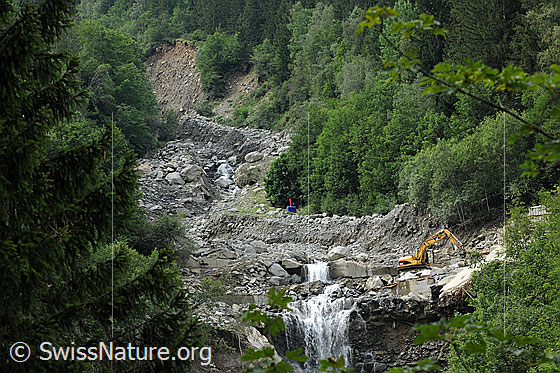 Foto: Murgang Spreitlaui (Spreitgraben, Spreitlauigraben, Grimselpass. Eine Galerie der Grimselpassstrasse wurde von den Gesteinsmassen verschüttet. Mit einem Bagger werden die gefährdete Galerie und die Überreste der Sperre zum Schutz der Transitgasleitung freigelegt.