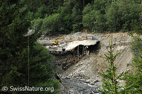 Foto: Naturgefahr Murgang Spreitgraben, Guttannen, nach den Murgängen. Unter den Geröllmassen befindet sich eine Galerie der Grimselpassstrasse. Mit einem Bagger werden die gefährdete Galerie und die Überreste der Sperre zum Schutz der Transitgasleitung freigelegt.