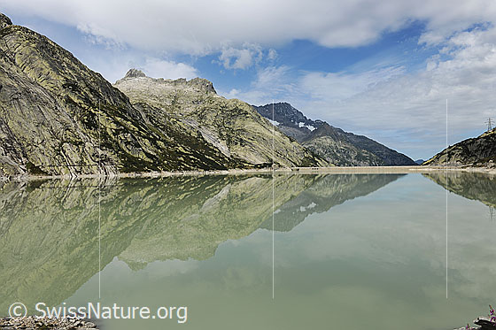 Foto: Symmetrische Spiegelung im Stausee. Alplistock und Ritzlihorn spiegeln sich im Räterichsbodensee und lassen interessante Muster und Formen entstehen.