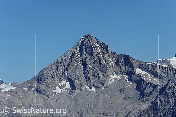 Foto: Bergpyramide Bietschhorn. Der markante Berg aus Fels ragt in den blauen Himmel.