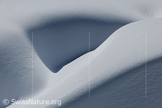 Foto: Kunst im Schnee. Ausschnitt aus einer Schneeverwehung mit interessanter Form, welche durch den Lichteinfall und den Schattenwurf erst richtig zur Geltung kommt.