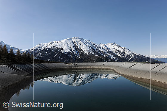 Foto: Spiegelung der Berge im Ausgleichsbecken eines Wasserkraftwerks (erneuerbare Energie).