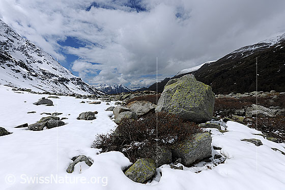 Foto: Wolkenstimmung über Naturlandschaft mit Felsblöcken und Schneeresten.
