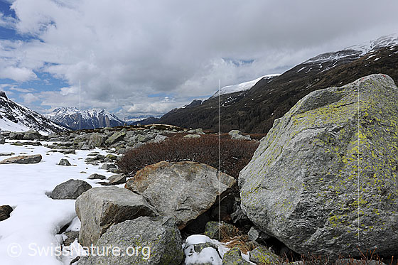 Foto: Wolkendecke über Berglandschaft mit Felsblöcken und Schneeresten.
