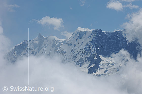 Foto: Alpengipfel mit Wolkenstimmung. Durch eine Wolkenlücke wird die Sicht auf Gletscherhorn und Äbeni Flue frei.