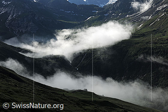 Foto: Berglandschaft mit Wolkenstimmung im Morgenlicht. Leichte Restbewölkung liegt über den Tälern.