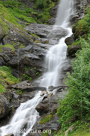 Foto: Wasserfall als Langzeitbelichtung. Das erfrischende Wasser fällt über unterschiedlich hohe Felsstufen in grüner Umgebung.