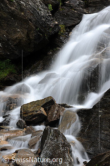 Foto: Wasserfall in Bergbach (Langzeitbelichtung). Das helle, fliessende Wasser bildet einen schönen Kontrast zu den dunklen Felsen im Bach.