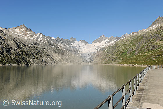 Foto: Das Quellgebiet der Aare: Oberaarsee und Oberaargletscher. In der Wasserfläche des Stausees spiegelt sich die Berglandschaft. 
Der Oberaarsee ist Teil eines Pumpspeicherwerks. Die Pumpspeicherwerke gewinnen für die Speicherung von aus Sonnenlicht und Windkraft erzeugter Energie an Bedeutung.