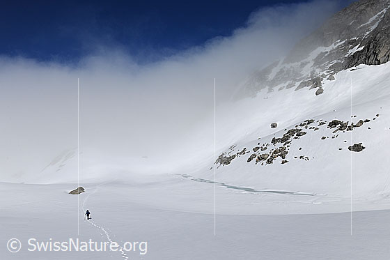 Foto: Alpinwanderer unterwegs auf weiter Hochebene mit Wolkenstimmung.