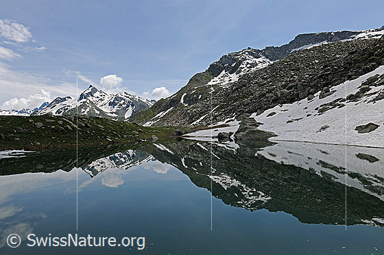 Foto: Schaplersee mit symmetrischer Spiegelung der Berglandschaft mit Schneefeldern.