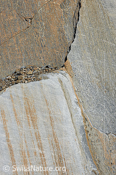 Foto: Felsstrukturen. Auf einem kleinen Vorsprung liegen Kieselsteine.