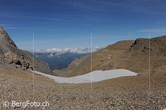 Foto: Blick vom Schnidejoch Richtung N (Saananland).
Die Berglandschaft ist karg. In der weiten Geröllhalde liegt ein Schneefeld.