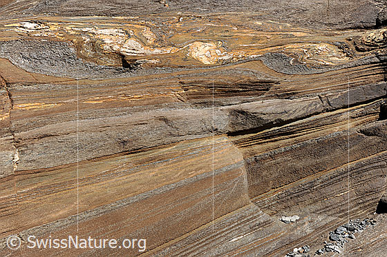 Foto: Ockerfarbener, geschichteter Fels.
