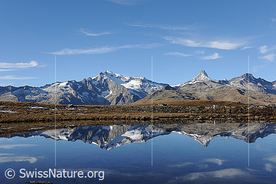 Foto: Spiegelung der Berner Alpen in Bergsee. Am Himmel sind ein paar Schleierwolken zu sehen.