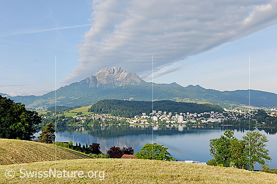 Foto: Pilatus mit Wolkenschweif. In der Bildmitte der Luzernersee (Teil des Vierwaldstättersees) und Luzern.